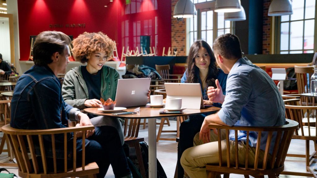 Eine Gruppe von Studenten sitzt in einem Cafe und unterhalten sich.
