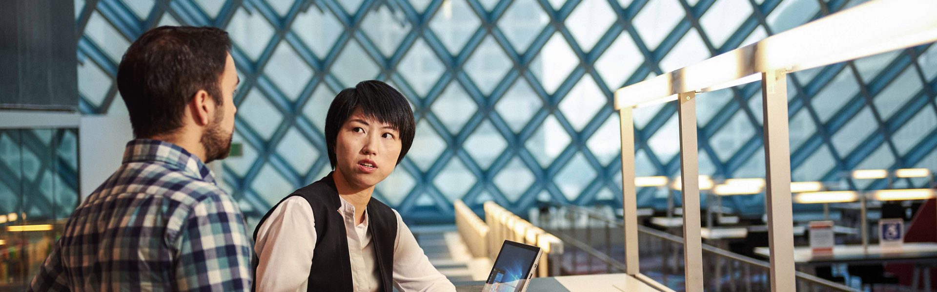 Woman and man sitting at a desk having a conversation in the Seattle Public Library with Surface Pro 4. Woman and man sitting at a desk having a conversation in the Seattle Public Library with Surface Pro 4.