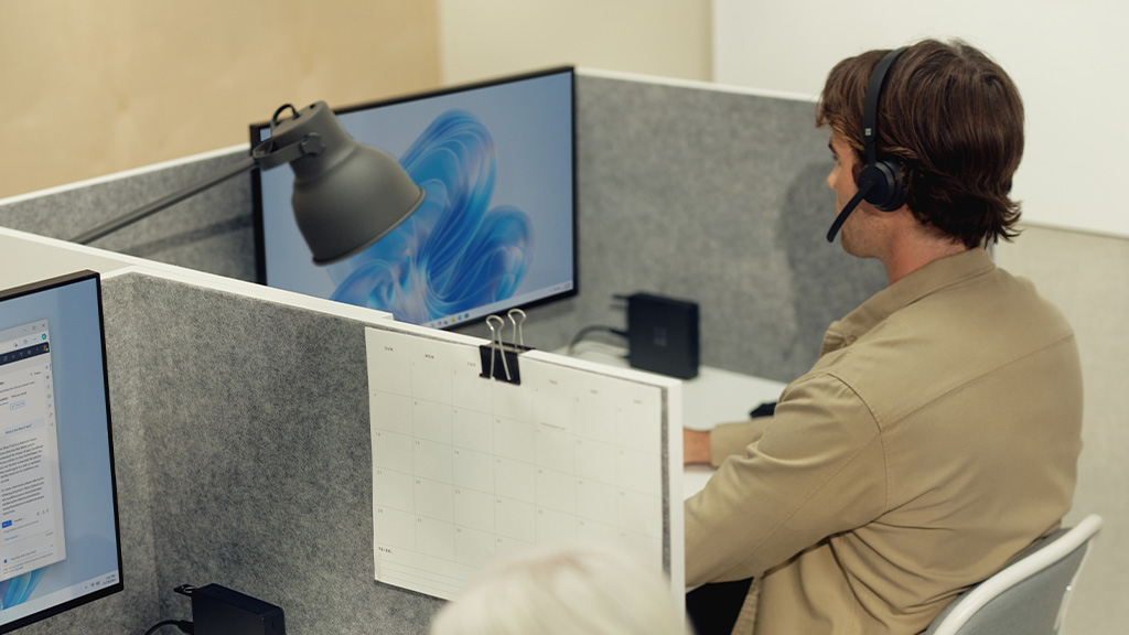 A man wearing a headset and sitting at a desk
