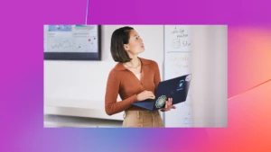 Woman holding laptop looking at board