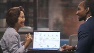 A woman and man sitting at a table with a laptop