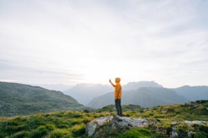 Young man takes photo with cell phone at sunrise on an alpine meadow.
