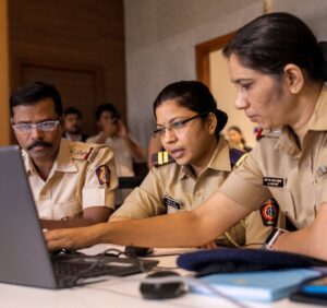 Three police officers looking at a laptop screen.