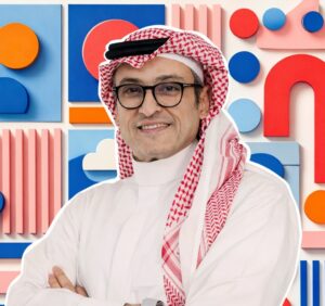 A portrait of a smiling man wearing a traditional Saudi ghutra, or red-and-white checked headdress.