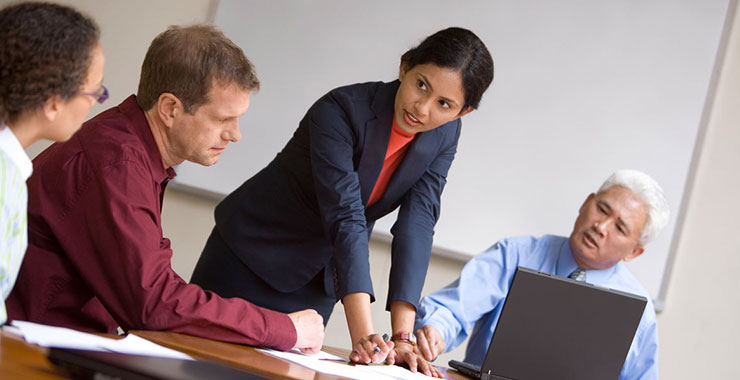 a group of people sitting at a table using a laptop computer