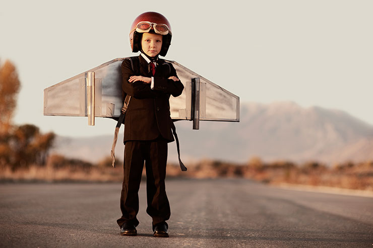 A young boy with a helmet and wings on his back.