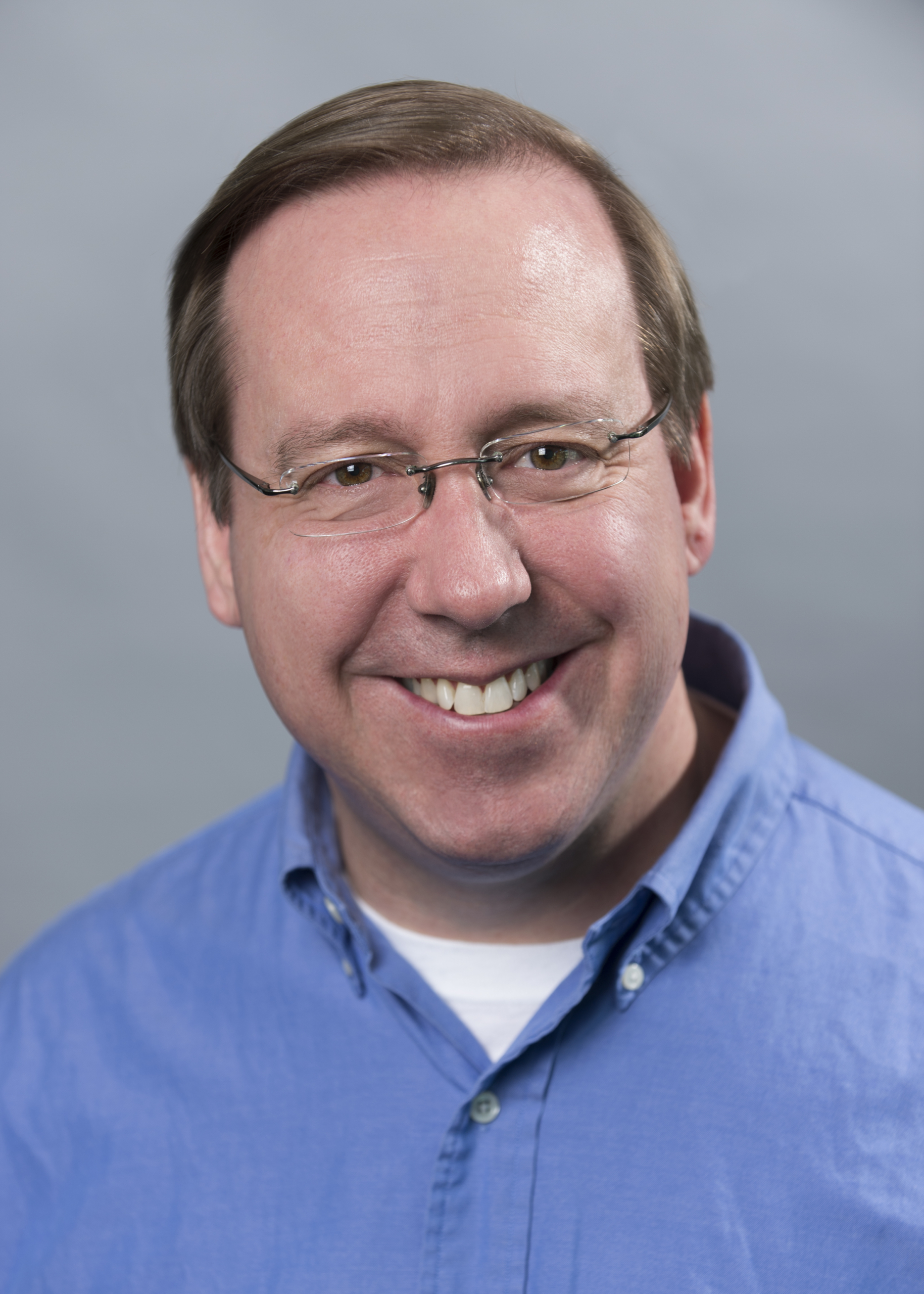 a close up of a man wearing glasses and looking at the camera