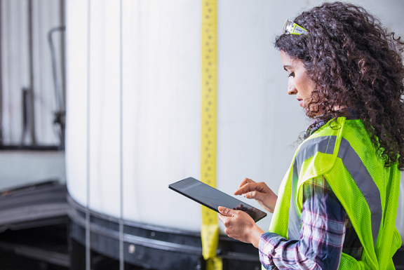 A field service worker in a yellow reflective vest working on a Microsoft tablet.
