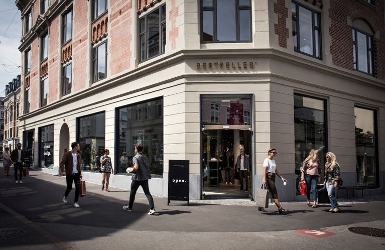 Customers walking by a Bestseller storefront.