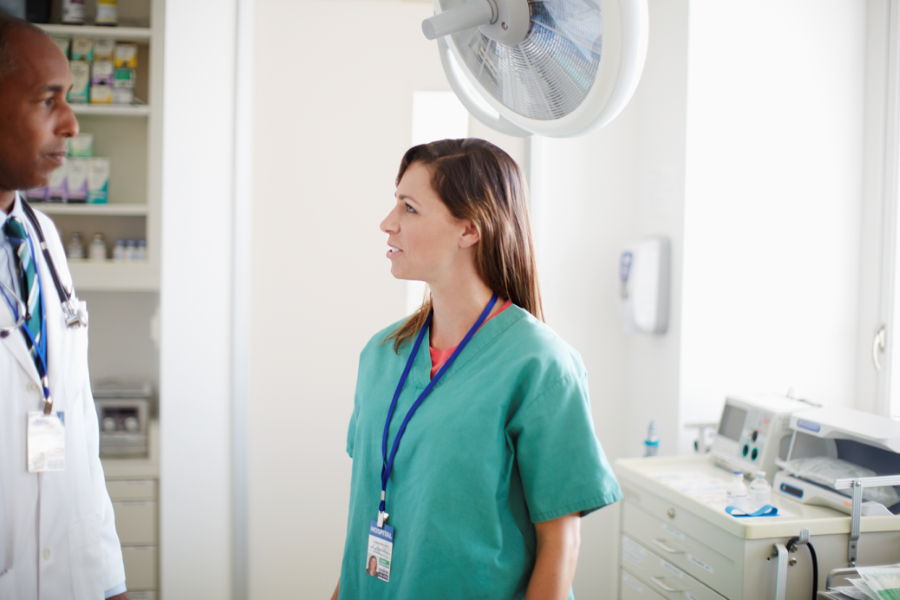 Two healthcare employees talking in a hospital room.