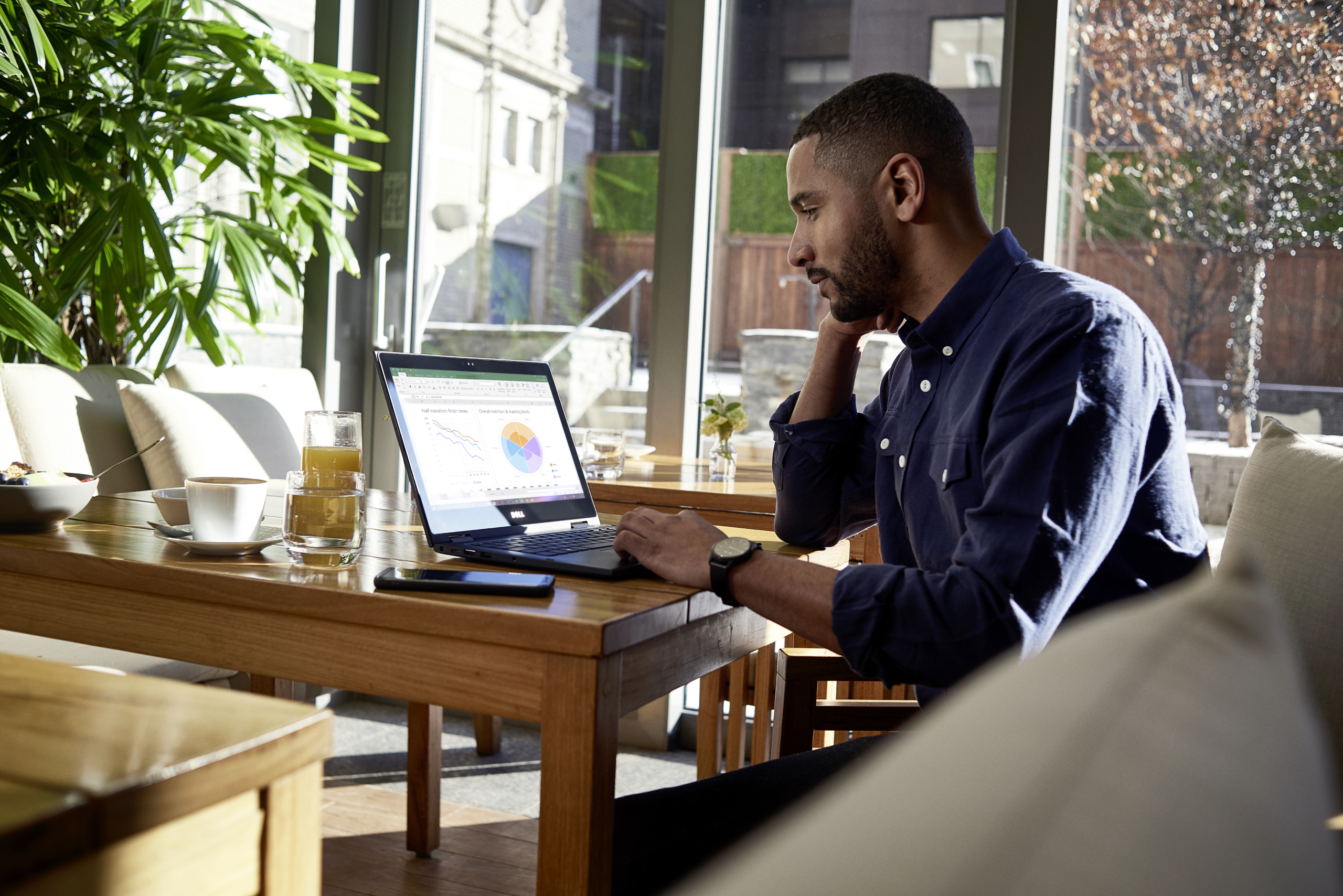 Male business professional at breakfast on a Dell device running Microsoft Excel