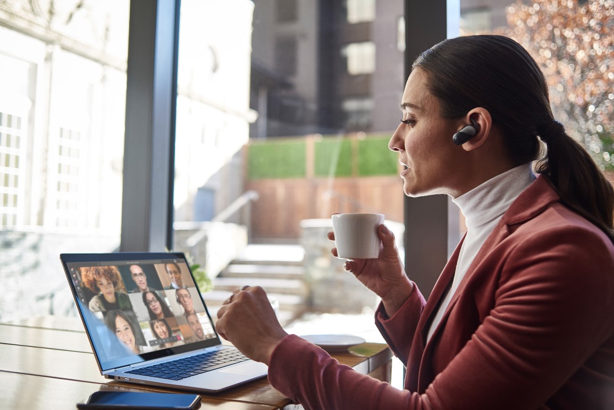 Female small business executive using HP Elite device running Microsoft Teams conference call. Different screens are available: one featuring 1 person on screen, another with 9 people on screen. Keywords: Microsoft Teams, Bluetooth, coffee.