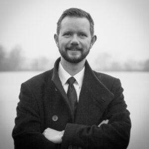 a man wearing a suit and tie smiling and looking at the camera