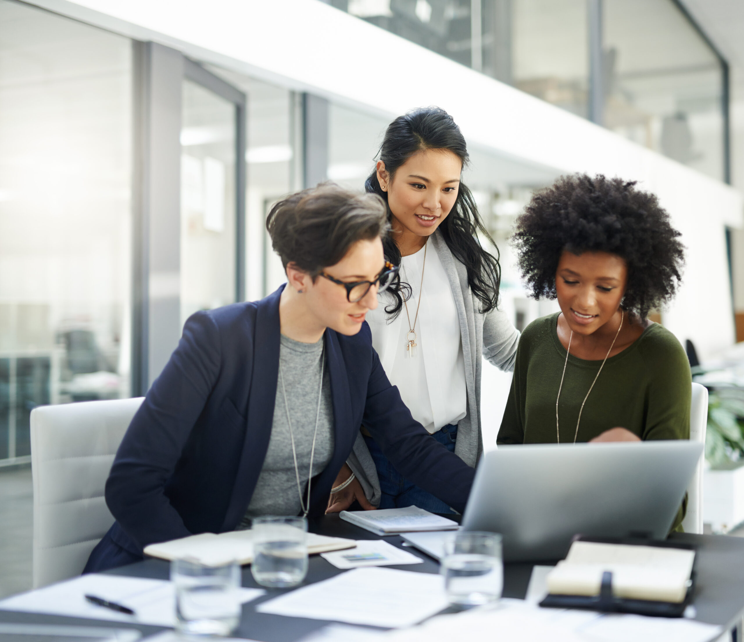 Photo of three businesswomen working at a laptop computer.