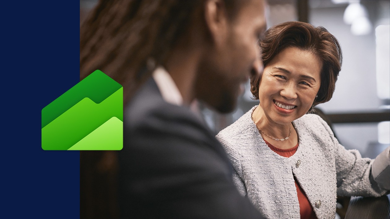 A man and woman smiling in an office setting. There's a wide dark blue border on the left side of the image with the Dynamics 365 Finance icon overlaid.