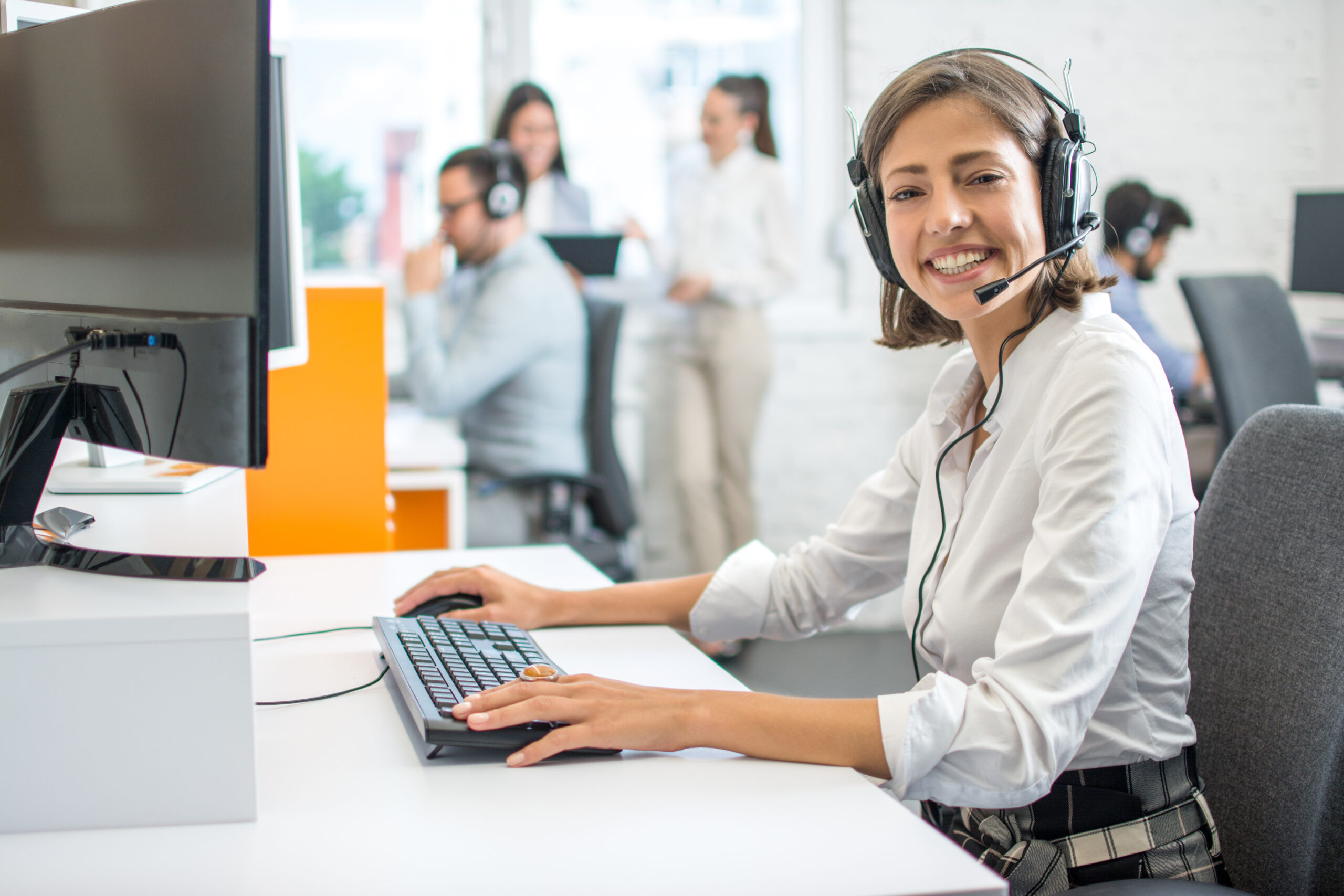 A woman wearing a headset and sitting at a desk with a computer