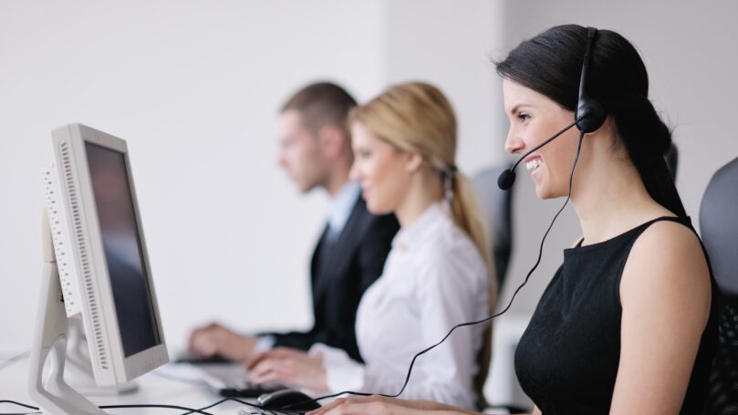 A woman wearing a headset and sitting at a computer