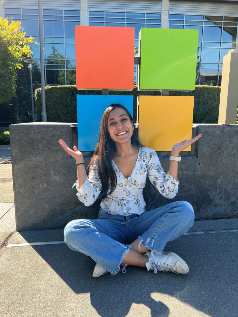 A woman sitting cross legged in front of Microsoft logo