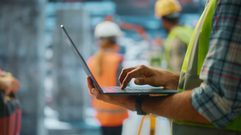 Construction manager using laptop typing on keyboard in building site