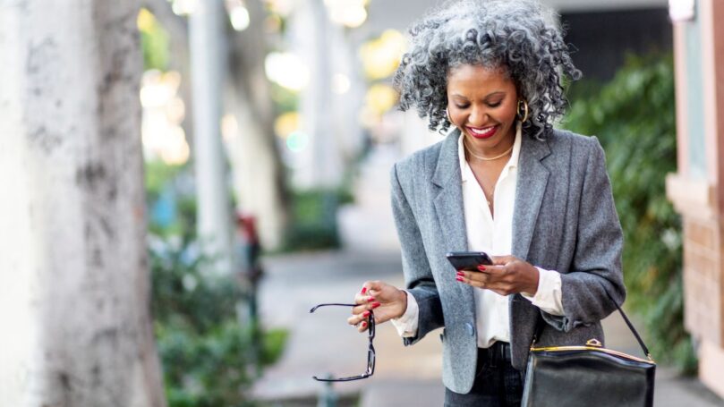 A business leader texting while walking in a city.