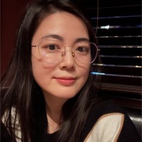 Person with glasses sitting indoors facing the camera