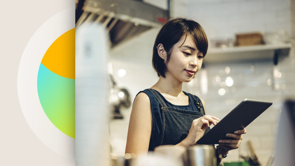 A female retail employee works on a tablet in her shop.
