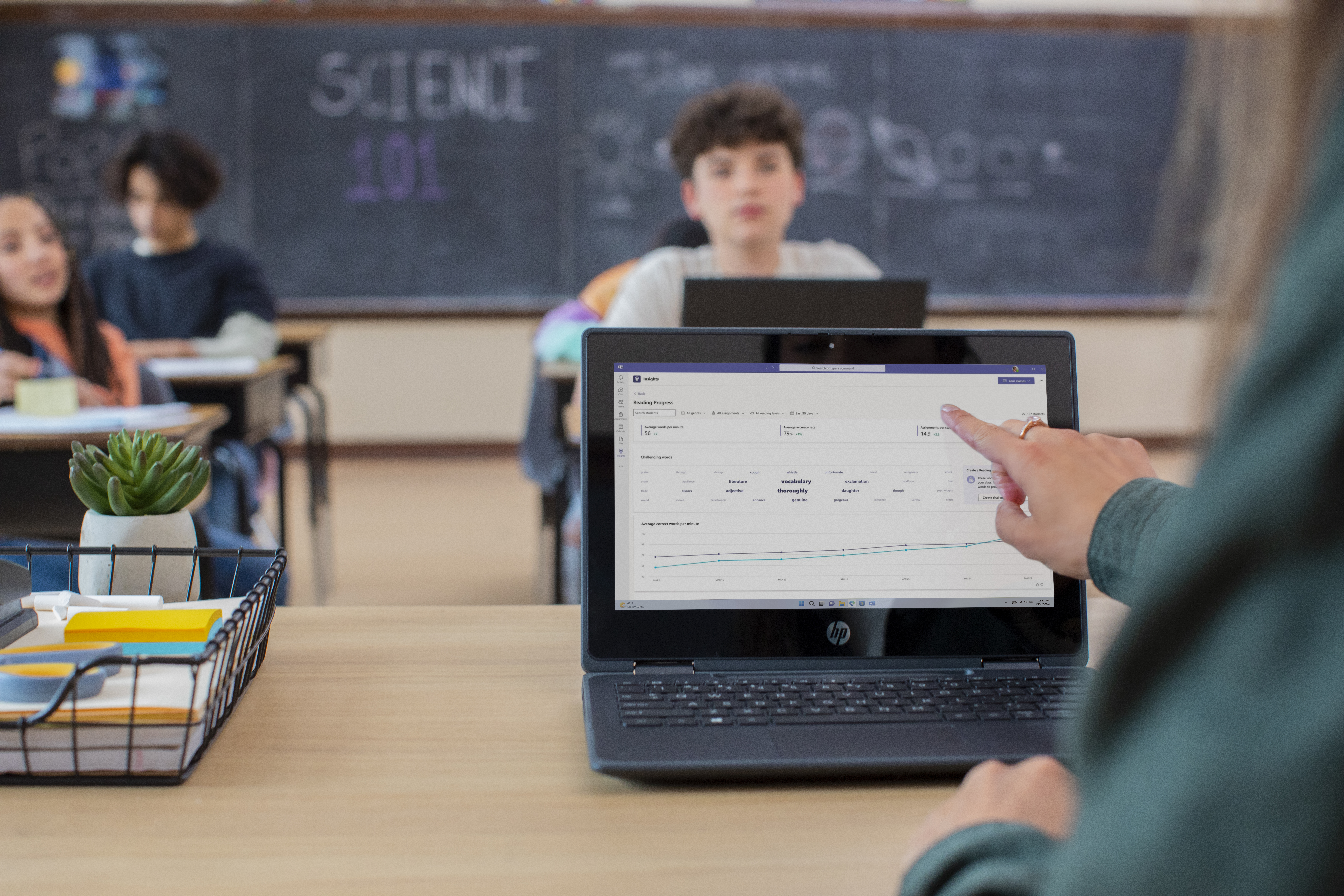 A teacher reviews Education Insights while students sit at their desks in a classroom.