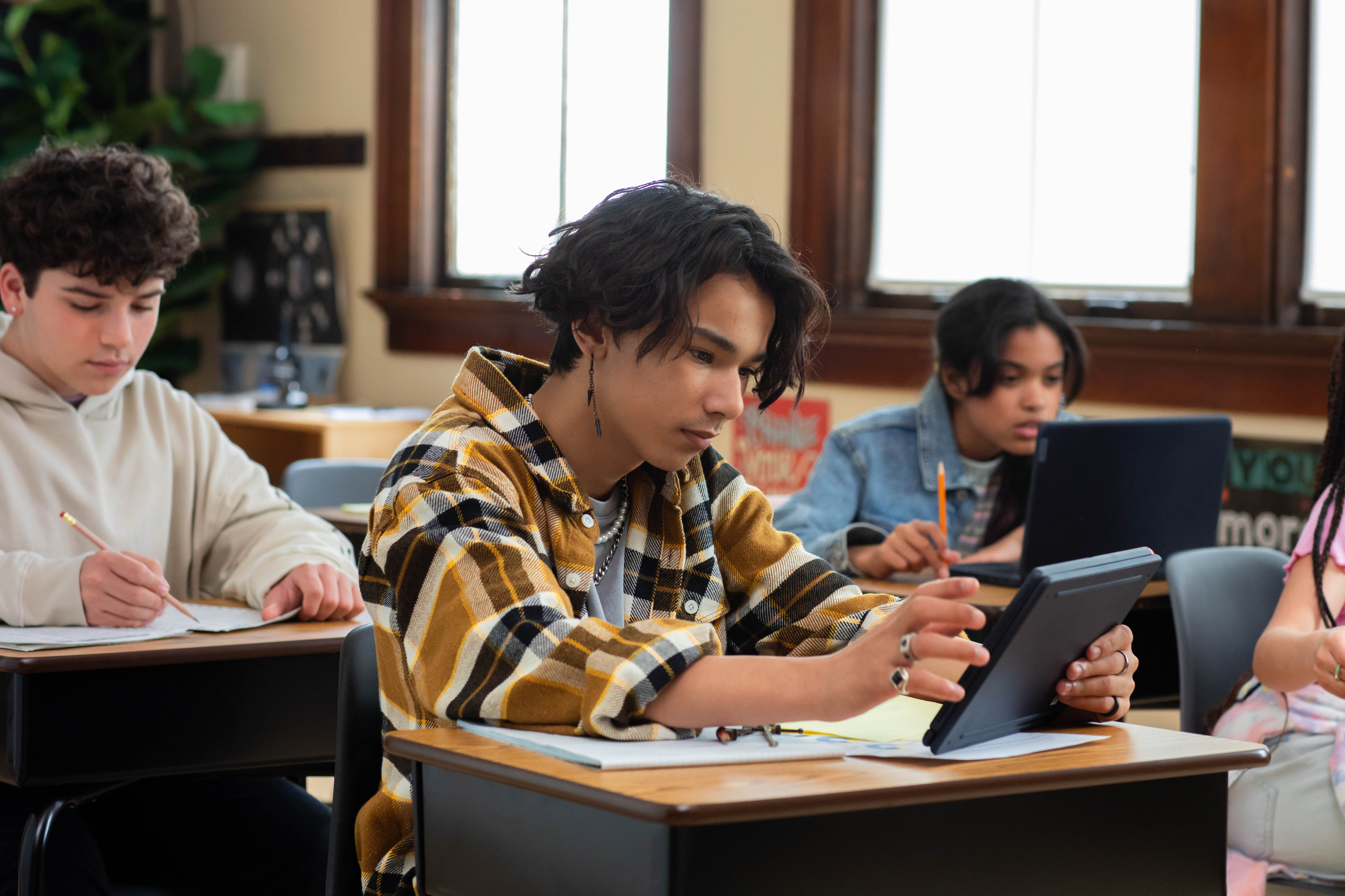 Students sitting at desks in a school classroom and working on laptops.
