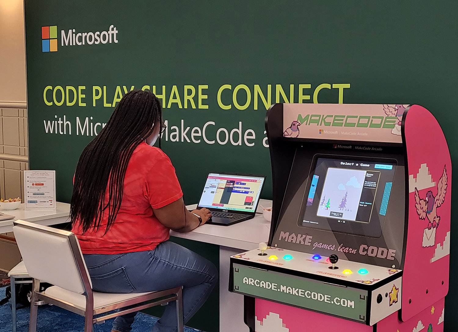 A person at a conference using a laptop to code a video game.