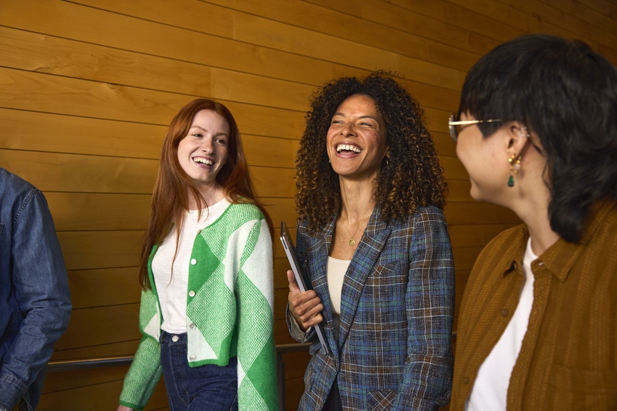 An instructor and students talking and walking together in a hallway at a higher education institution.