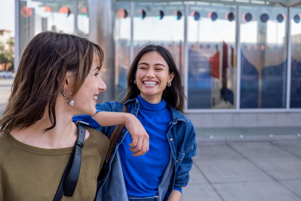 Two older students laughing together outside of a building.