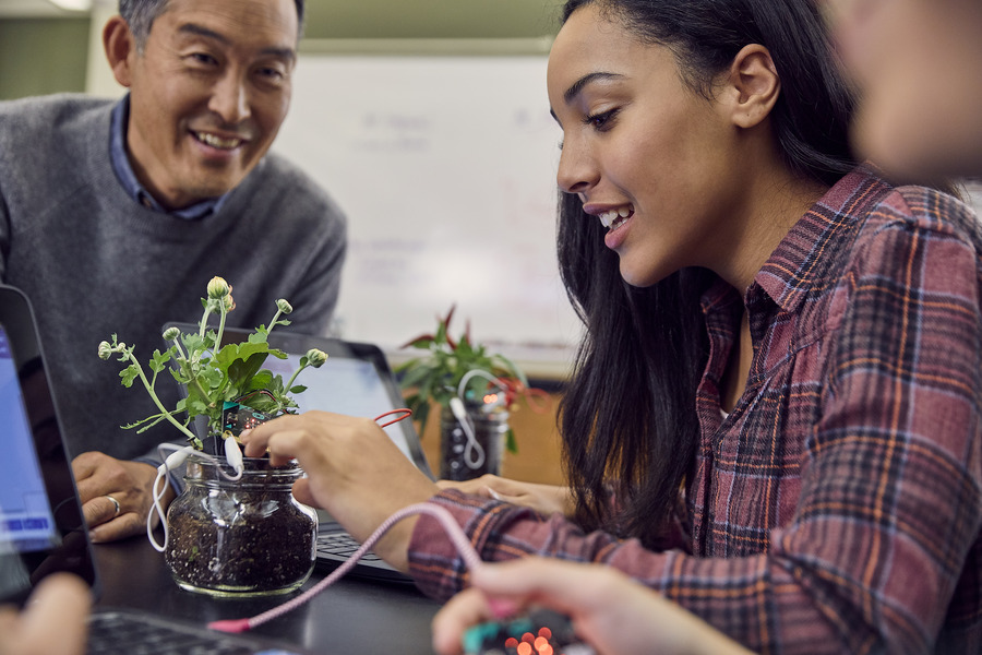A student and educator looking at a plant.