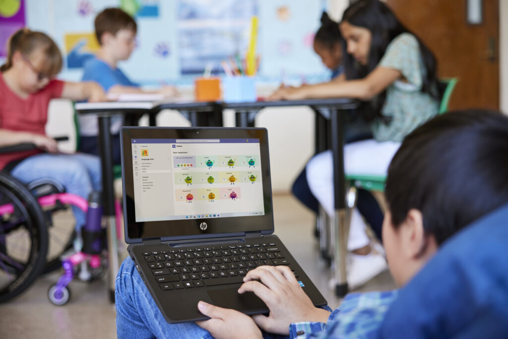 A student working on a laptop in a classroom full of students. 