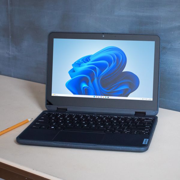 An open laptop on a table in a school classroom.