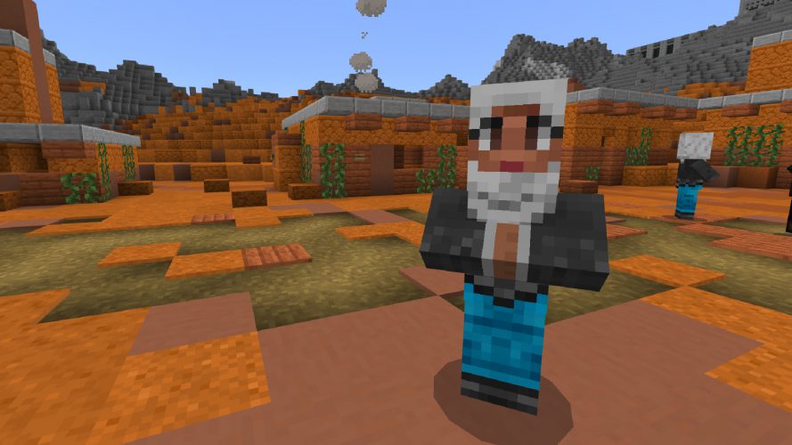 A bearded man stands in a settlement in the desert.