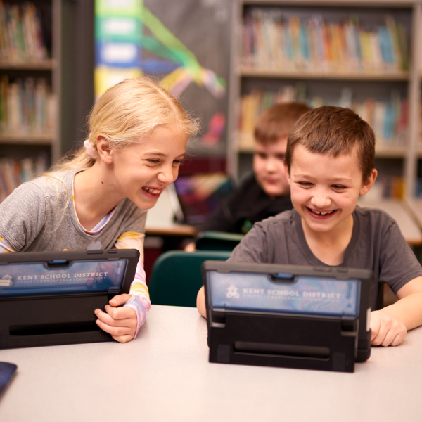 Young students play Minecraft together on laptops in a school classroom.