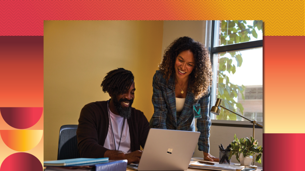 Two education leaders working together on a laptop in a school office.