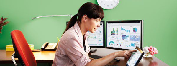A woman sitting near her work desk interacting with a touch screen device