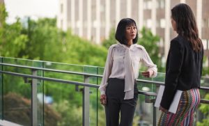 To professionally dressed women talking outside a building.