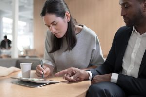 Two people sitting at a desk analyzing a Surface tablet together