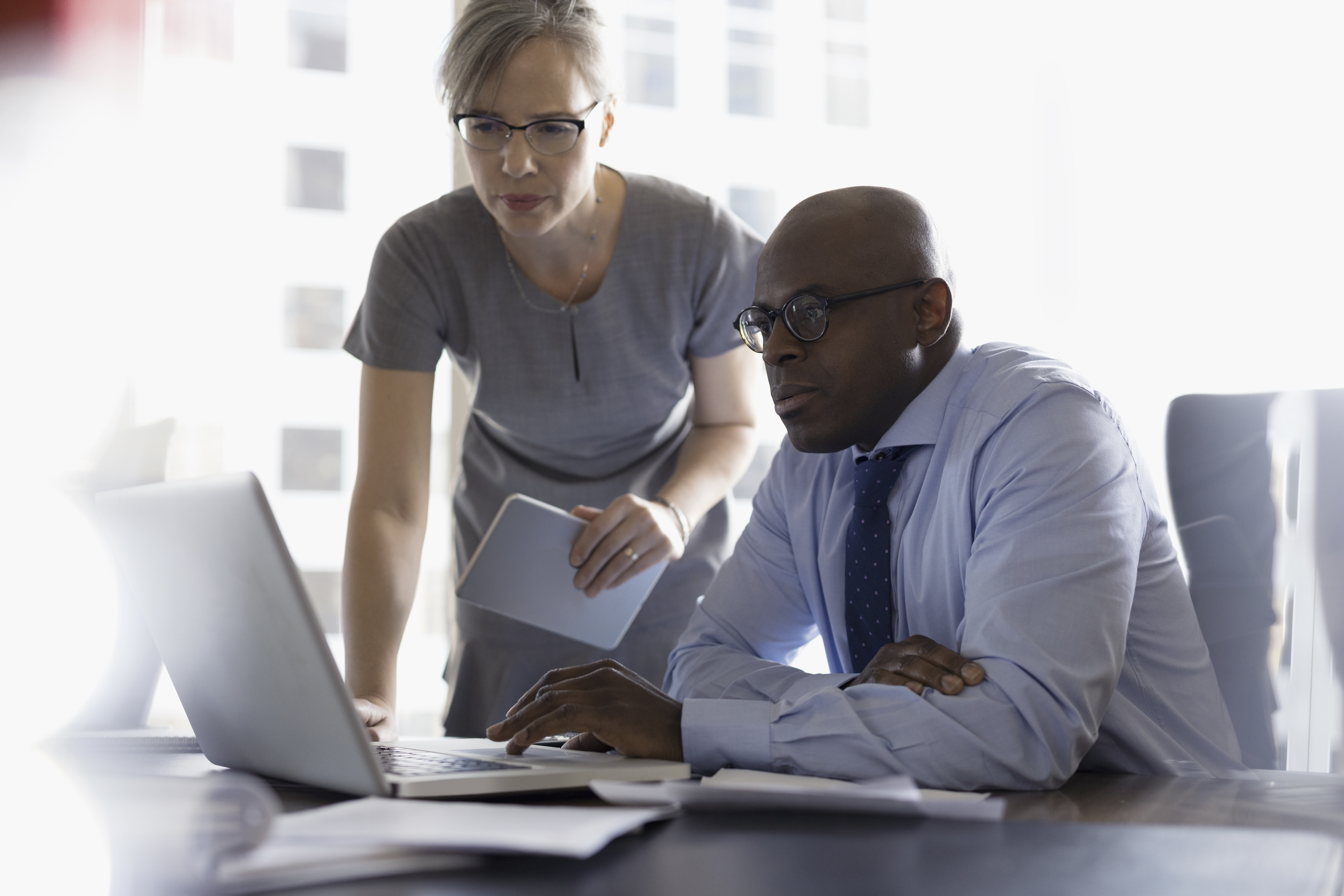 Two people working at laptop in office
