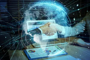 Two hands shaking in front of computer monitor