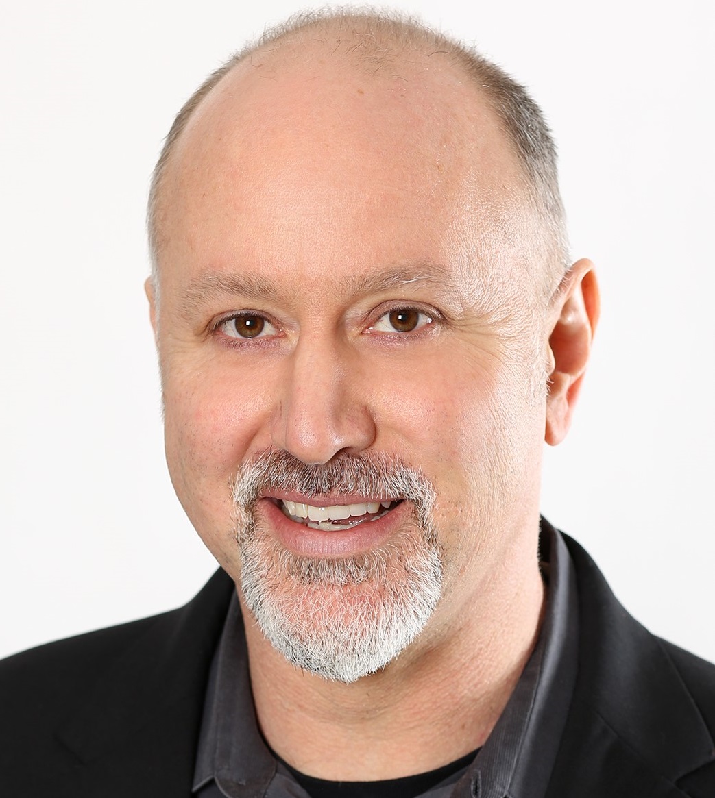 a man wearing a suit and tie smiling and looking at the camera