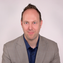 a man wearing a suit and tie smiling at the camera