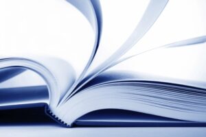 Close-up of an open book with flipping pages. Blue-toned.
