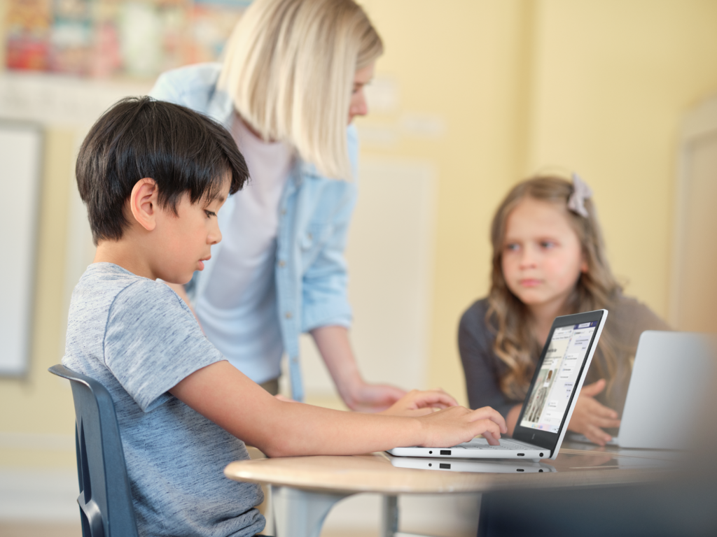 教室でPCを操作する生徒と教師