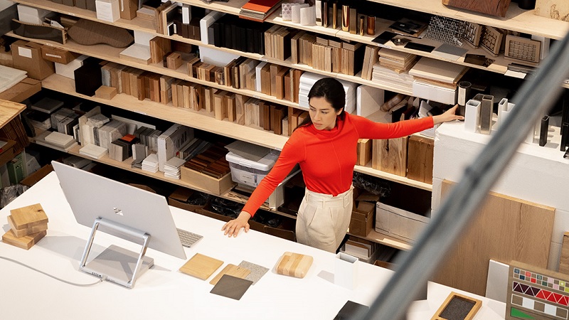 Ein Mitarbeiter im Lebensmitteleinzelhandel steht hinter einer Theke und gibt Essen aus. Er trägt Handschuhe und einen Mund-Nasen-Schutz.