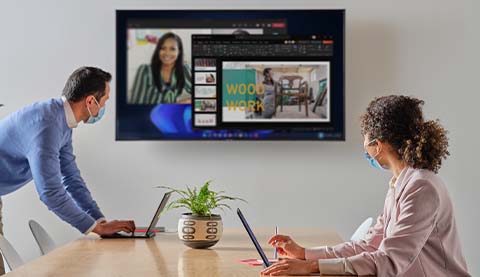 Two people in a meeting room looking at a presentation