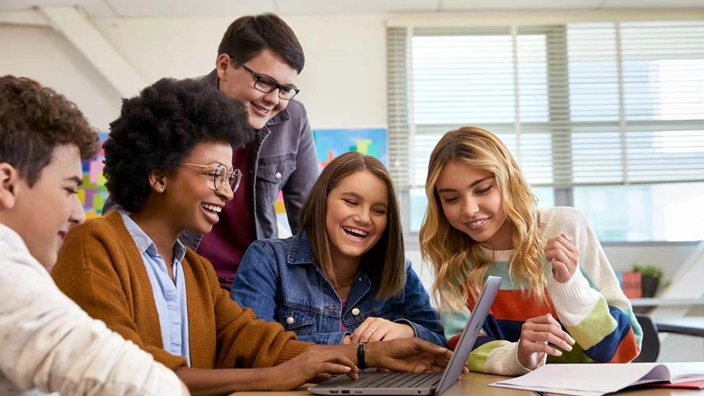 Fünft Schüler*innen blicken auf ein Surface Laptop.
