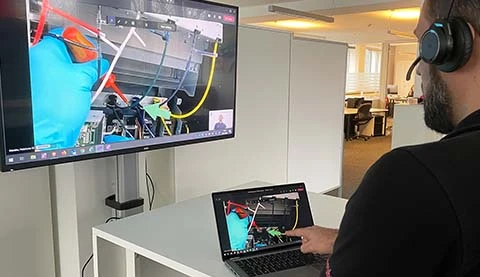 Ein Mann von hinten vor einem Tablet PC und einem gro&szlig;en Bildschirm an der Wand. 